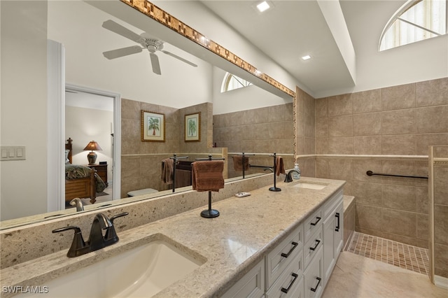 ensuite bathroom featuring double vanity, a sink, tile walls, and connected bathroom