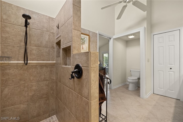 bathroom with baseboards, tiled shower, toilet, ceiling fan, and tile patterned floors