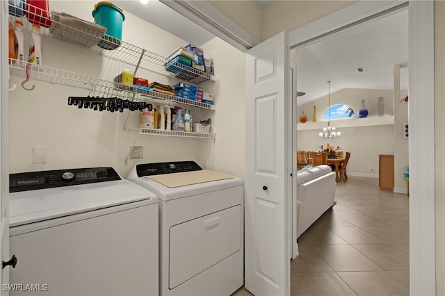 laundry room with an inviting chandelier, laundry area, washing machine and clothes dryer, and light tile patterned floors