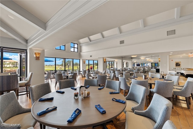 dining space with high vaulted ceiling, hardwood / wood-style flooring, visible vents, and beam ceiling