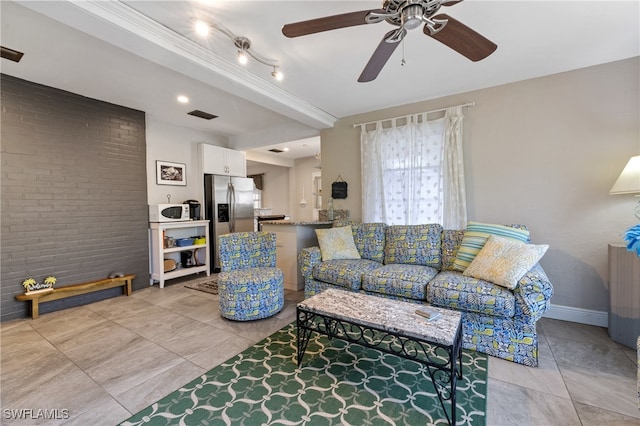 living room with ornamental molding, brick wall, light tile patterned floors, and ceiling fan