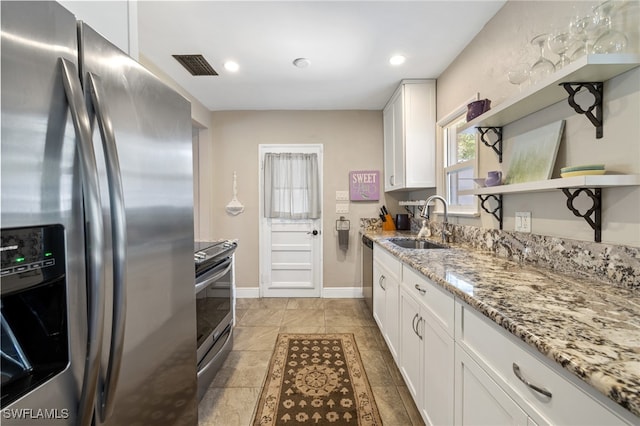 kitchen with light stone countertops, white cabinetry, appliances with stainless steel finishes, and sink