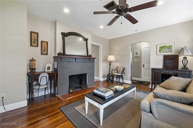 living room featuring ceiling fan, a fireplace, and dark hardwood / wood-style flooring