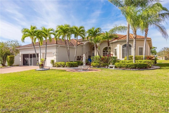 mediterranean / spanish home featuring a garage and a front lawn