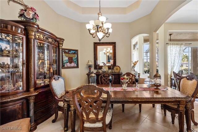 dining room featuring tile patterned flooring, a notable chandelier, and a raised ceiling