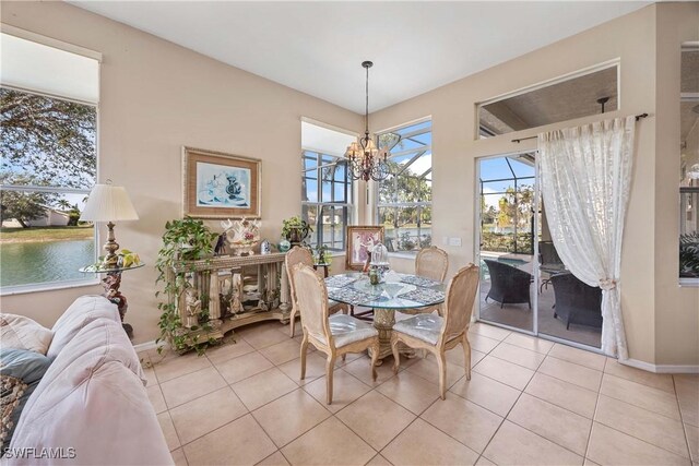 dining area with a water view, a chandelier, and light tile patterned floors