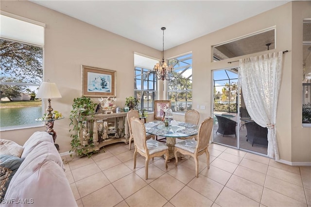 dining space with a water view, a notable chandelier, baseboards, and light tile patterned floors