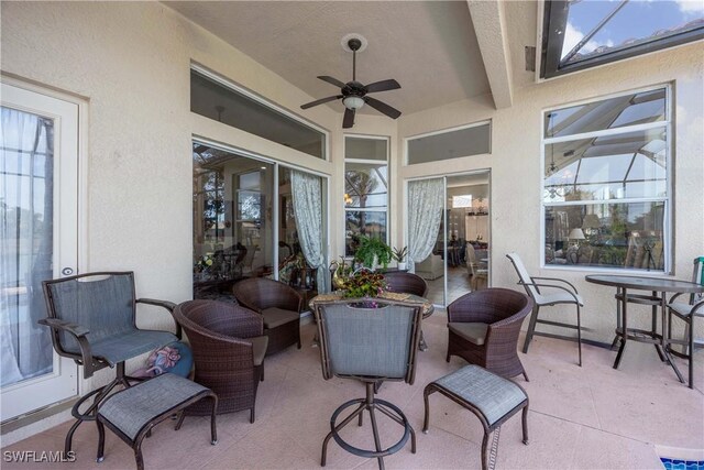 view of patio / terrace featuring ceiling fan, an outdoor hangout area, and glass enclosure