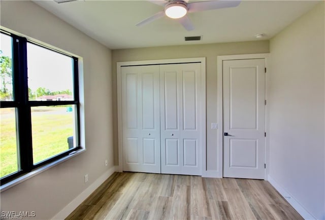 unfurnished bedroom featuring ceiling fan, light hardwood / wood-style floors, and a closet