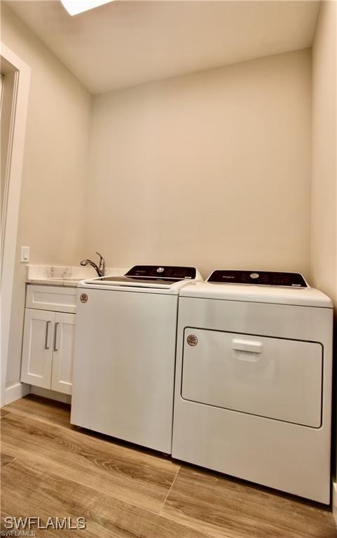 washroom featuring cabinets, washer and clothes dryer, light hardwood / wood-style flooring, and sink