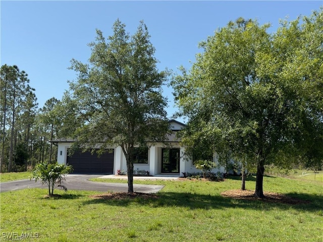 view of property hidden behind natural elements with a garage and a front lawn