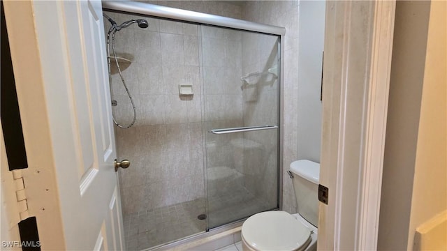 bathroom featuring a shower with shower door and toilet