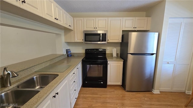 kitchen with light hardwood / wood-style floors, sink, white cabinetry, and stainless steel appliances