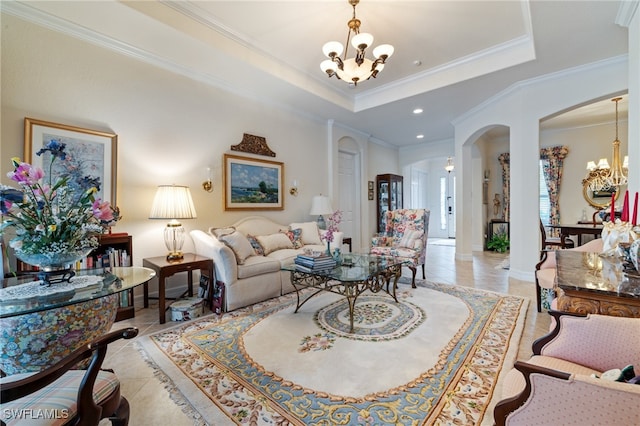 tiled living room featuring crown molding, a tray ceiling, and an inviting chandelier