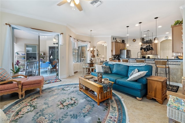 tiled living room featuring ornamental molding and ceiling fan with notable chandelier