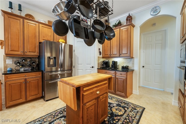 kitchen with decorative backsplash, stainless steel fridge with ice dispenser, crown molding, and light tile patterned flooring