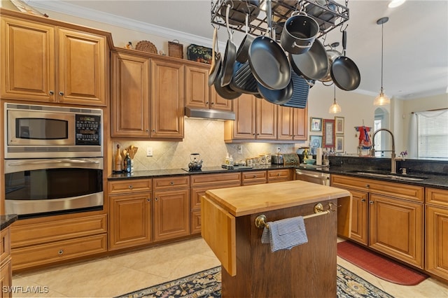 kitchen featuring decorative light fixtures, stainless steel appliances, tasteful backsplash, sink, and butcher block countertops