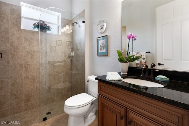 bathroom featuring tile patterned floors, toilet, a walk in shower, and vanity