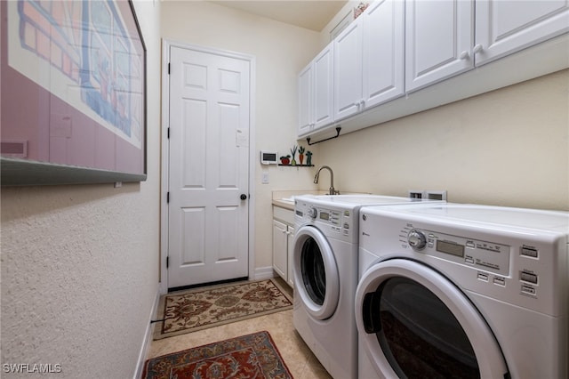 clothes washing area with washer and clothes dryer, light tile patterned floors, baseboards, a sink, and cabinet space