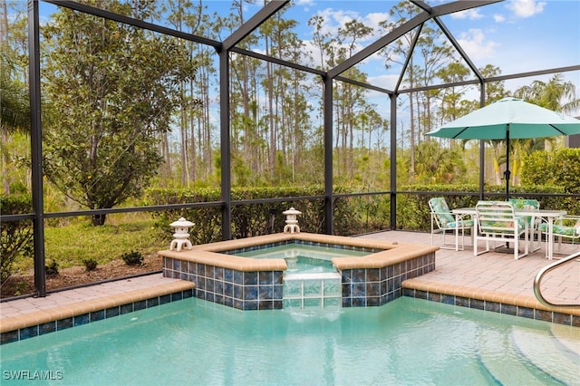 view of pool featuring glass enclosure, an in ground hot tub, and a patio area