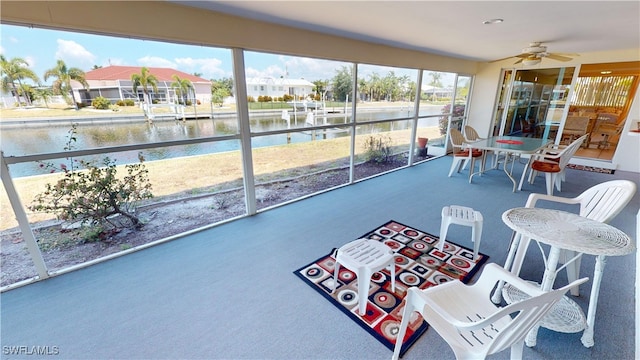 sunroom / solarium featuring ceiling fan, a water view, and a healthy amount of sunlight