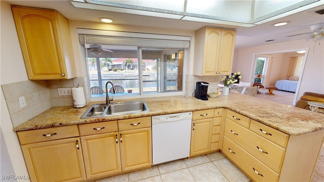 kitchen featuring backsplash, kitchen peninsula, sink, white dishwasher, and light brown cabinetry