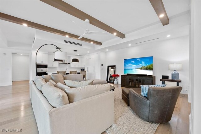 living room featuring ceiling fan, beamed ceiling, and light wood-type flooring