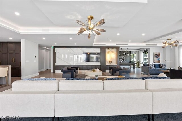 living room featuring an inviting chandelier, hardwood / wood-style floors, and a raised ceiling