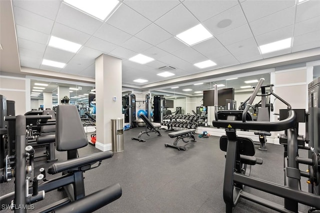 gym with visible vents, a paneled ceiling, and baseboards