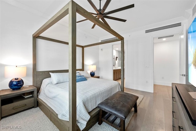 bedroom featuring wood finished floors and ensuite bathroom