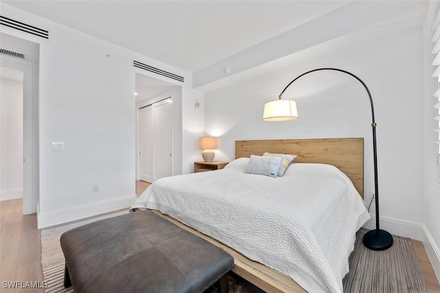 bedroom with visible vents, baseboards, and wood finished floors