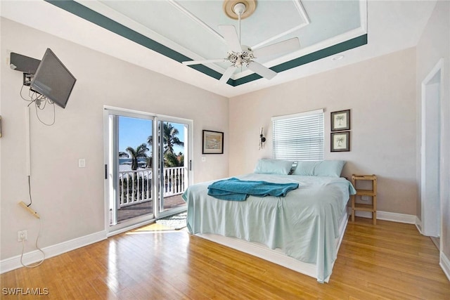 bedroom with ceiling fan, access to exterior, multiple windows, and hardwood / wood-style floors