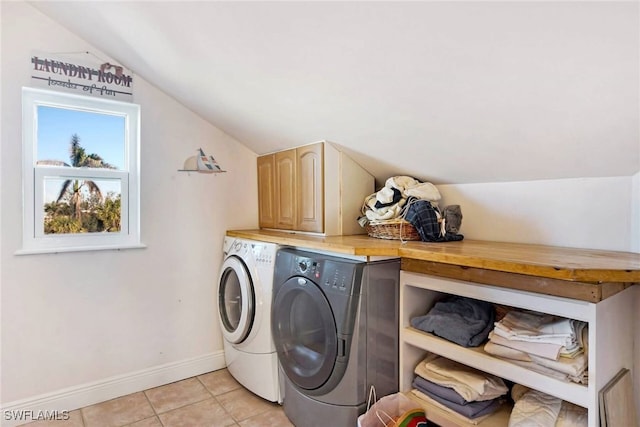 clothes washing area featuring washing machine and dryer, cabinets, and light tile patterned flooring