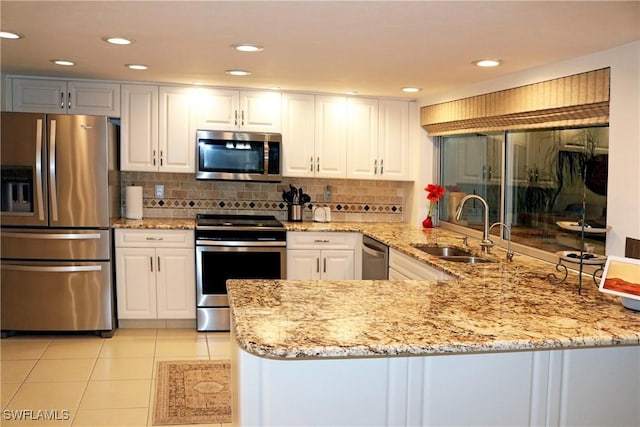 kitchen featuring sink, light tile patterned floors, appliances with stainless steel finishes, kitchen peninsula, and white cabinets