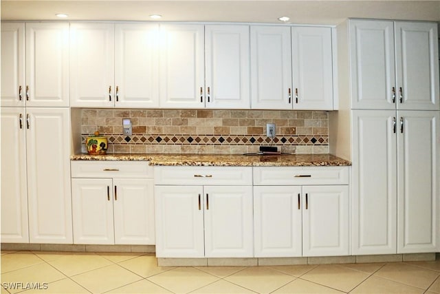 bar with white cabinetry, backsplash, light tile patterned flooring, and dark stone countertops