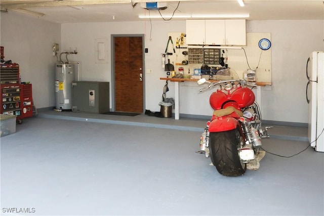 garage featuring a garage door opener, white fridge, electric water heater, and a workshop area