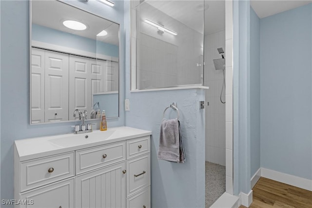 bathroom featuring vanity, wood-type flooring, and a tile shower