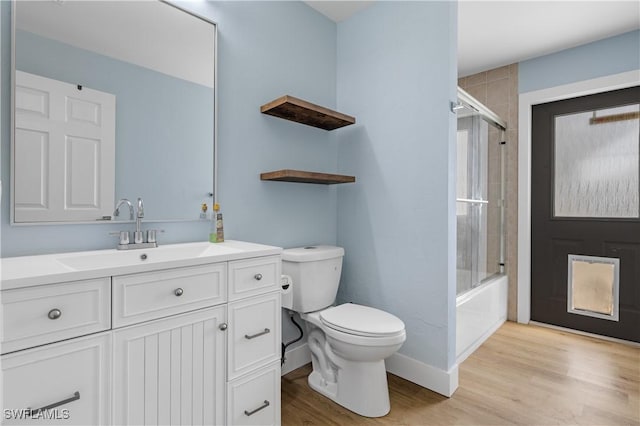 full bathroom with vanity, hardwood / wood-style floors, bath / shower combo with glass door, and toilet