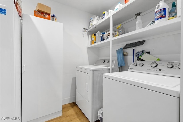 clothes washing area with washing machine and dryer and light hardwood / wood-style floors