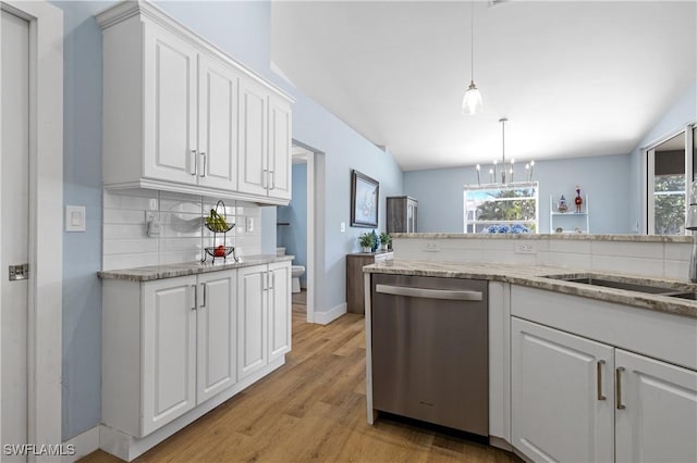 kitchen featuring pendant lighting, tasteful backsplash, white cabinetry, lofted ceiling, and stainless steel dishwasher