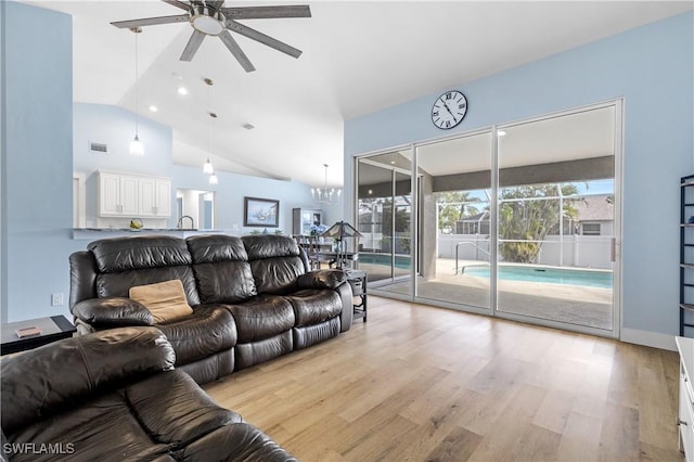 living room with lofted ceiling, ceiling fan with notable chandelier, and light hardwood / wood-style floors