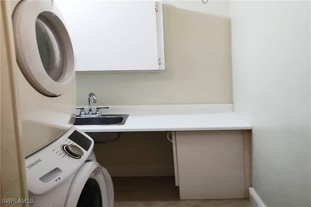 washroom with sink, cabinets, and stacked washer and clothes dryer