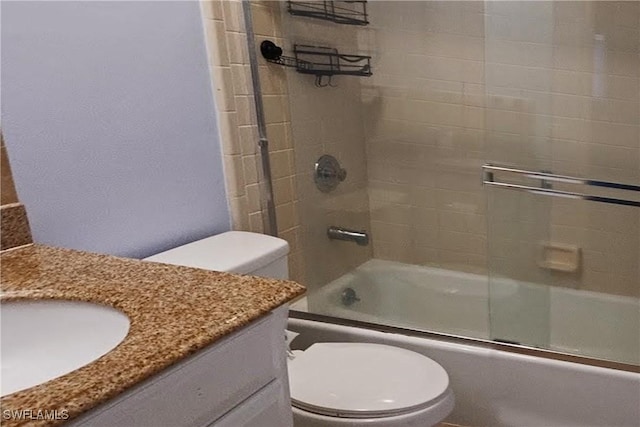 full bathroom featuring vanity, combined bath / shower with glass door, and toilet