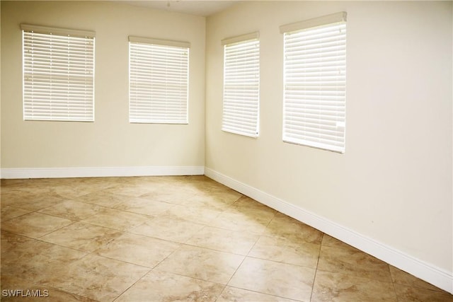 spare room with light tile patterned flooring and a wealth of natural light