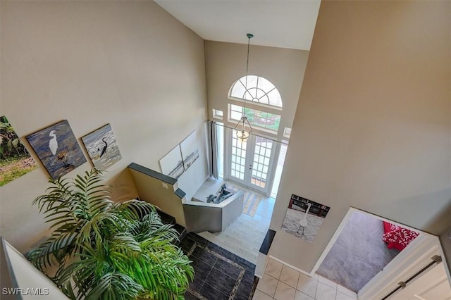 foyer with light tile patterned flooring, french doors, and high vaulted ceiling