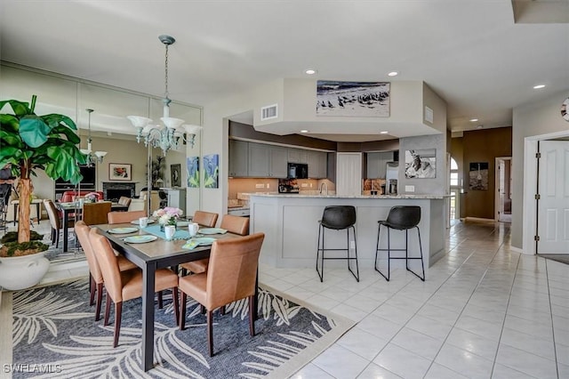 dining space featuring sink, light tile patterned floors, and a notable chandelier