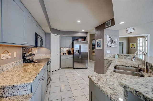 kitchen with light stone countertops, appliances with stainless steel finishes, gray cabinetry, sink, and backsplash