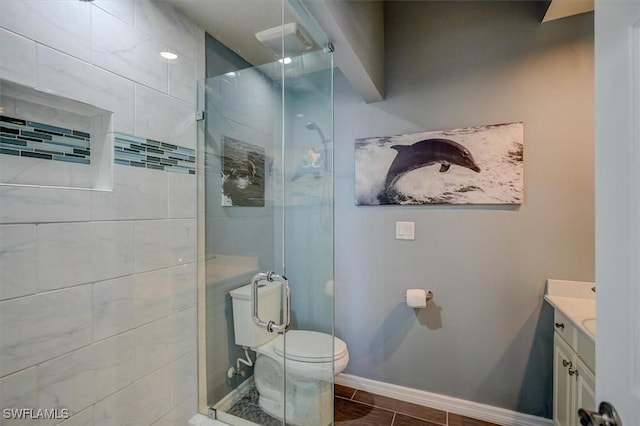 bathroom with toilet, vanity, a tile shower, and tile patterned flooring