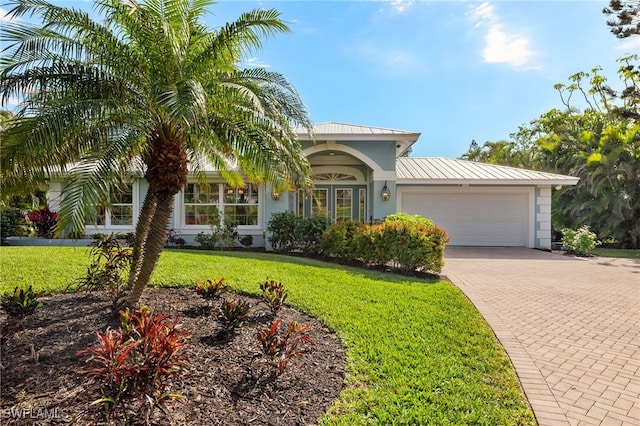 view of front of house with a front yard, decorative driveway, an attached garage, and stucco siding