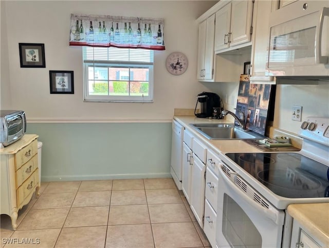 kitchen with white cabinetry, sink, light tile patterned flooring, and white appliances